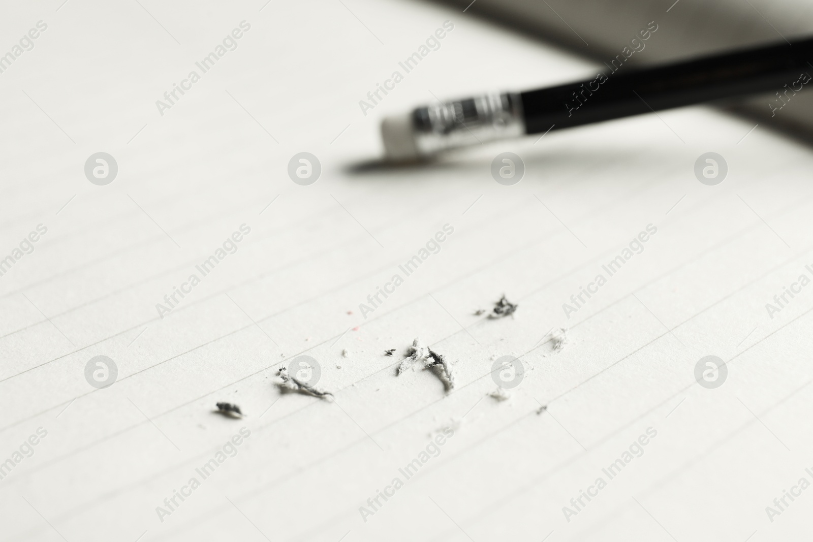 Photo of Pencil with eraser and scraps on copybook, selective focus