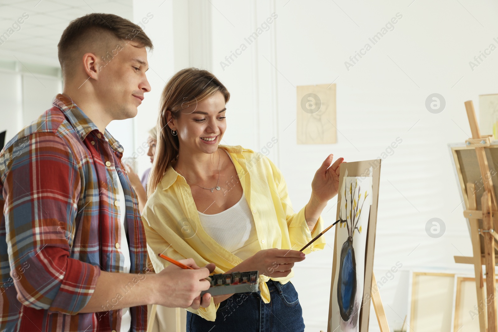 Artist teaching her student to paint in studio Photo of Artist teaching her student to paint in studio