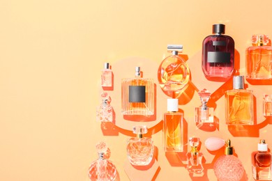 Photo of Different luxury perfumes on beige background, flat lay. Space for text