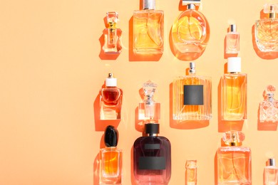 Photo of Different luxury perfumes on beige background, flat lay. Space for text