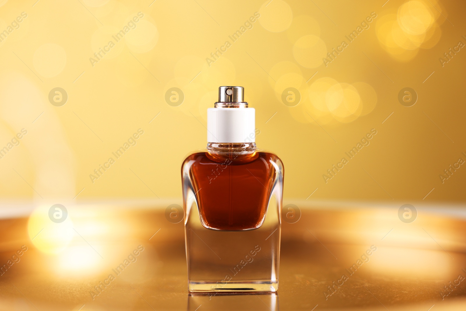 Bottle of aromatic perfume on metal tray against beige background with blurred lights, closeup. Bokeh effect Photo of Bottle of aromatic perfume on metal tray against beige background with blurred lights, closeup. Bokeh effect
