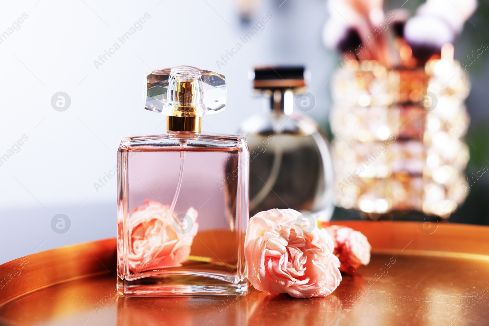 Bottle of aromatic perfume and flowers on metal tray against blurred background, closeup Photo of Bottle of aromatic perfume and flowers on metal tray against blurred background, closeup
