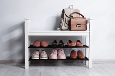 Photo of Stand with different stylish shoes and bags indoors