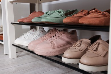 Photo of Stand with different stylish shoes indoors, closeup