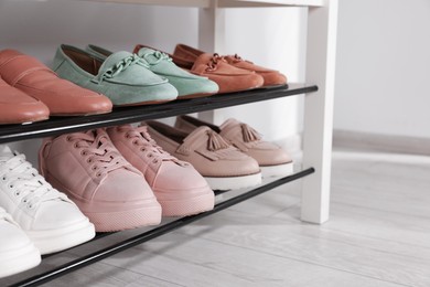 Photo of Stand with different stylish shoes indoors, closeup