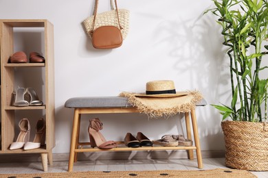 Photo of Stands with different stylish shoes, straw hats, bags and houseplant indoors