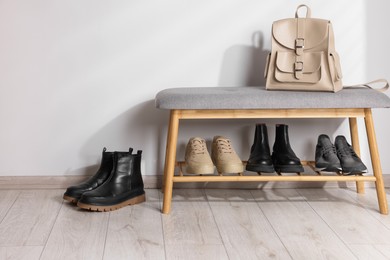 Photo of Stand with different stylish shoes and bag indoors