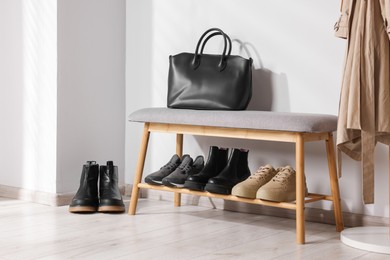 Photo of Stand with different stylish shoes and bag indoors