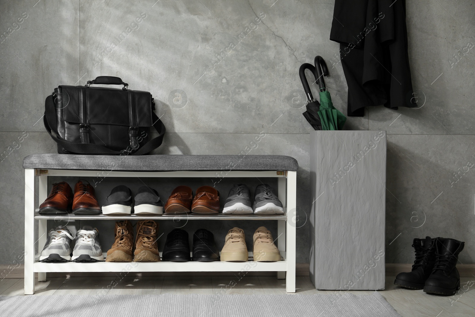 Shoe storage bench with different footwear, briefcase and umbrellas indoors Photo of Shoe storage bench with different footwear, briefcase and umbrellas indoors