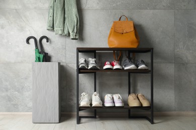 Photo of Shoe storage. Shelving unit with different footwear, backpack and umbrellas indoors