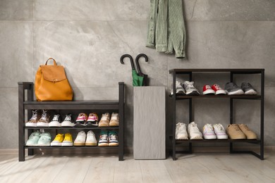 Photo of Shoe storage. Shelving units with different footwear, backpack and umbrellas indoors