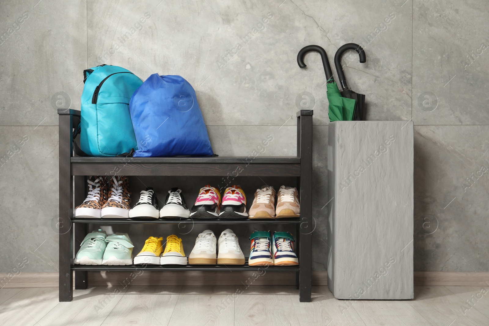 Shoe storage bench with different footwear, backpack, sport's bag and umbrellas indoors Photo of Shoe storage bench with different footwear, backpack, sport's bag and umbrellas indoors
