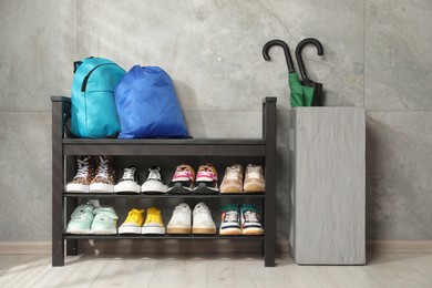 Photo of Shoe storage bench with different footwear, backpack, sport's bag and umbrellas indoors