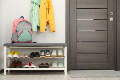 Photo of Shoe storage bench with different footwear and backpack indoors