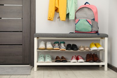 Photo of Shoe storage bench with different footwear and backpack indoors