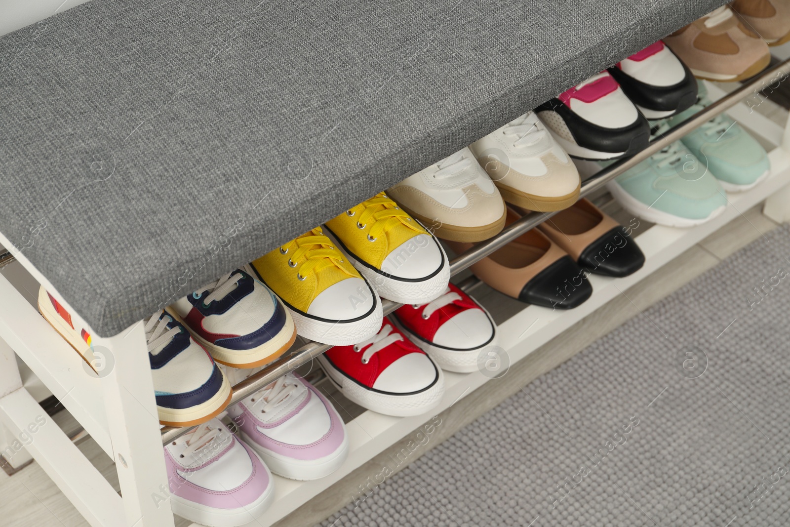 Shoe storage bench with different footwear indoors, closeup Photo of Shoe storage bench with different footwear indoors, closeup