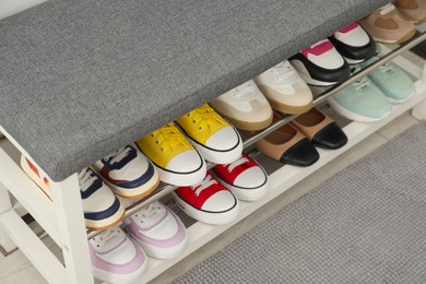 Photo of Shoe storage bench with different footwear indoors, closeup