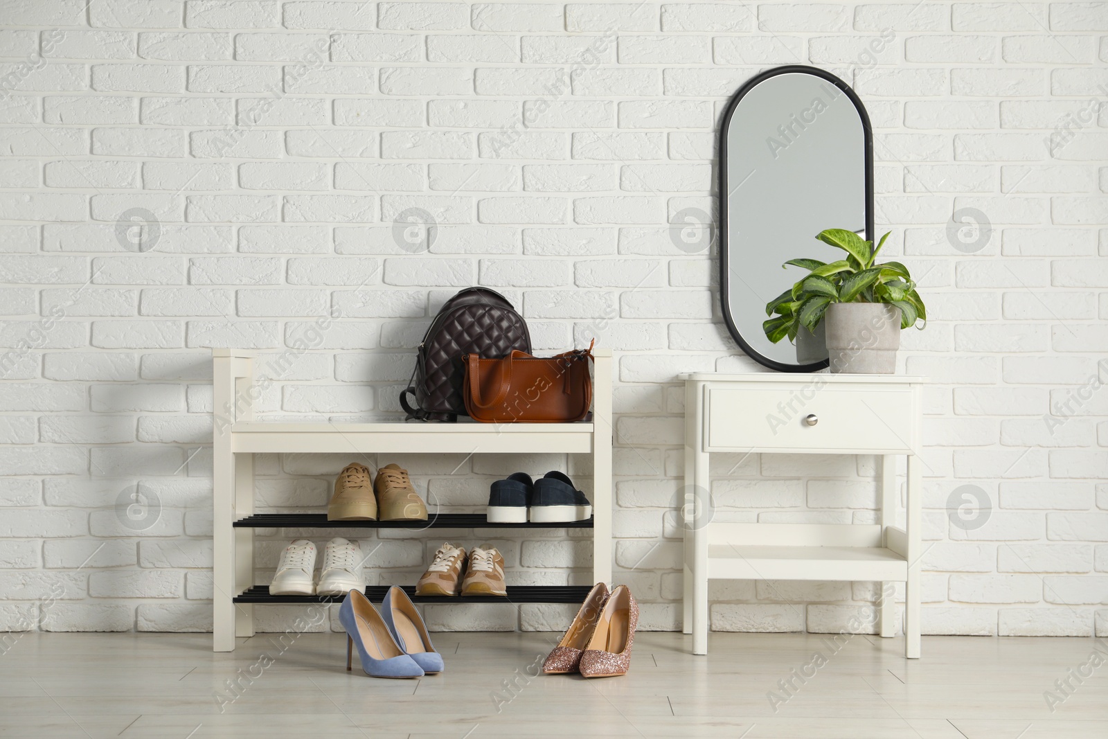 Shoe storage bench with different footwear and houseplant indoors Photo of Shoe storage bench with different footwear and houseplant indoors
