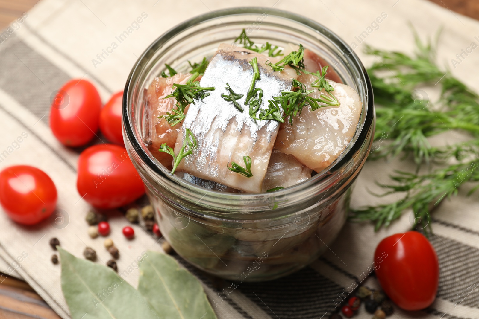 Pieces of delicious herring with dill in jar and tomatoes on table, closeup Photo of Pieces of delicious herring with dill in jar and tomatoes on table, closeup
