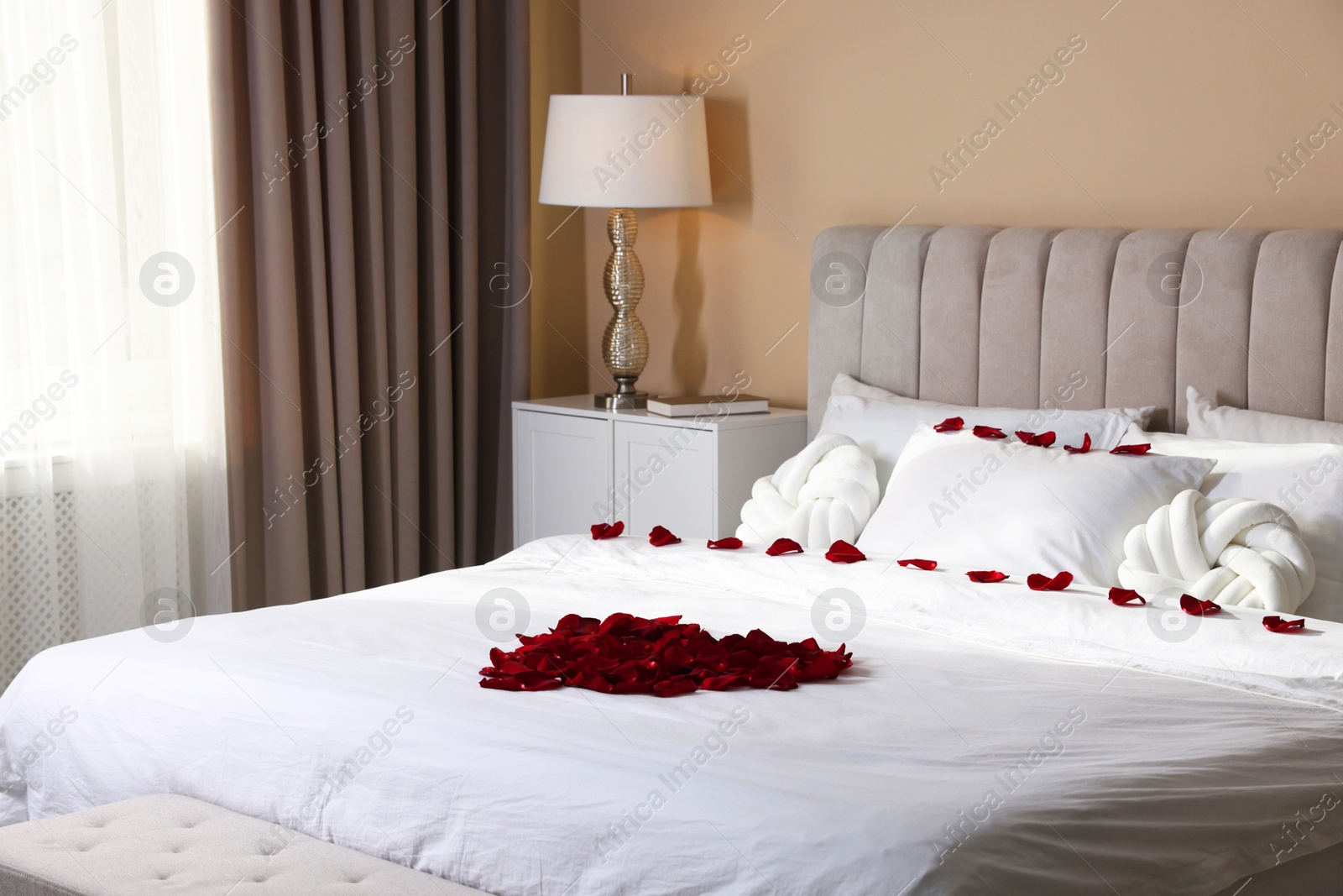 Heart made with beautiful rose petals on bed indoors Photo of Heart made with beautiful rose petals on bed indoors