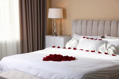 Photo of Heart made with beautiful rose petals on bed indoors