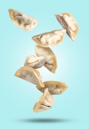 Image of Uncooked gyoza falling on light blue background
