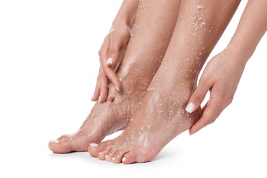 Photo of Woman applying body scrub onto her feet on white background, closeup