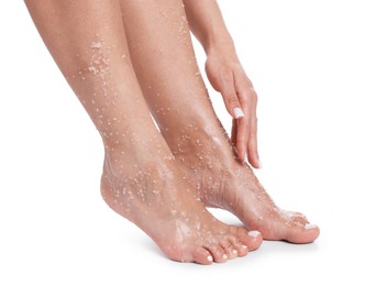 Photo of Woman applying body scrub onto her feet on white background, closeup