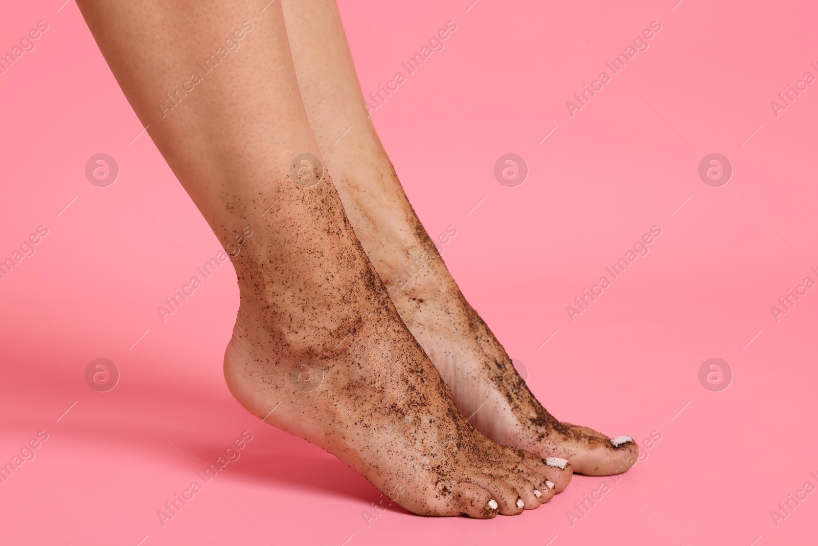 Woman with body scrub on her feet against pink background, closeup Photo of Woman with body scrub on her feet against pink background, closeup