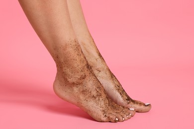 Photo of Woman with body scrub on her feet against pink background, closeup