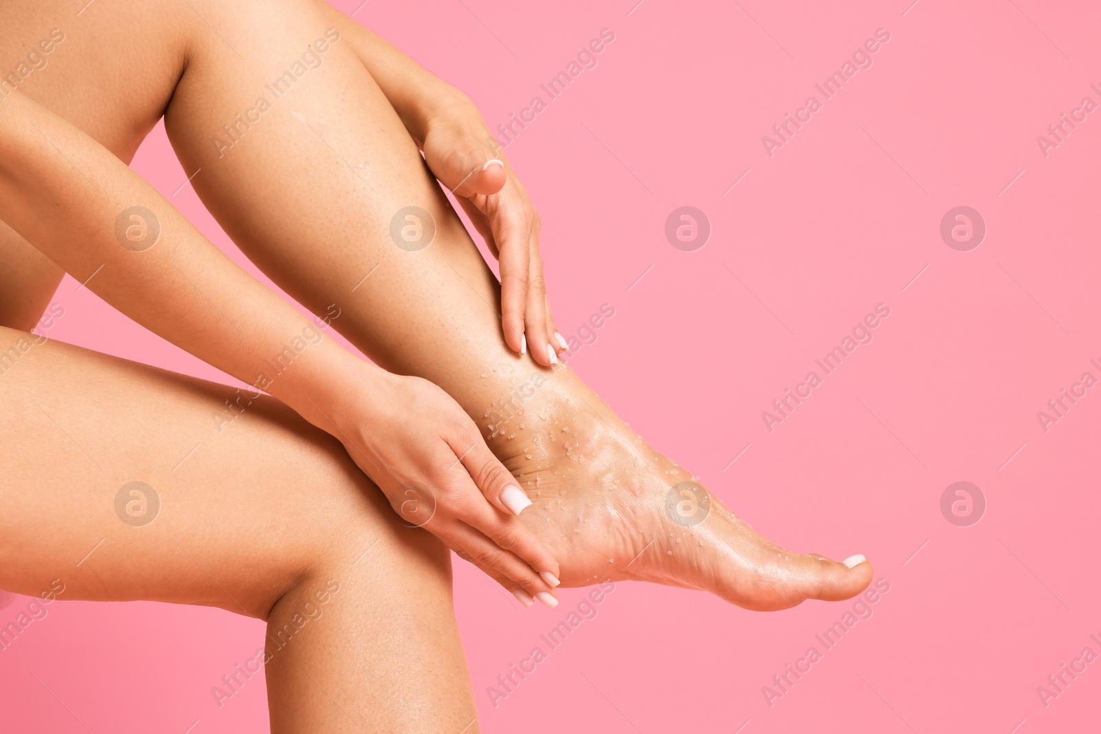 Woman applying body scrub onto her foot on pink background, closeup Photo of Woman applying body scrub onto her foot on pink background, closeup