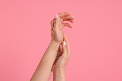 Photo of Woman applying body scrub onto her hands on pink background, closeup