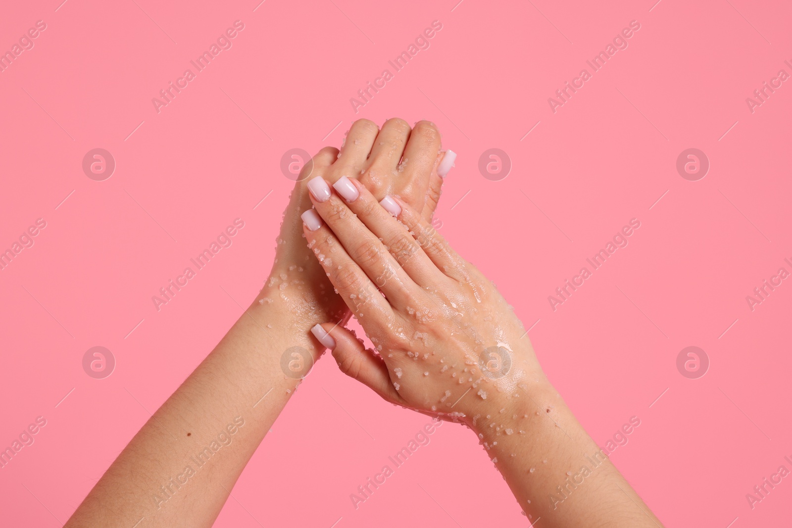 Woman applying body scrub onto her hands on pink background, closeup Photo of Woman applying body scrub onto her hands on pink background, closeup