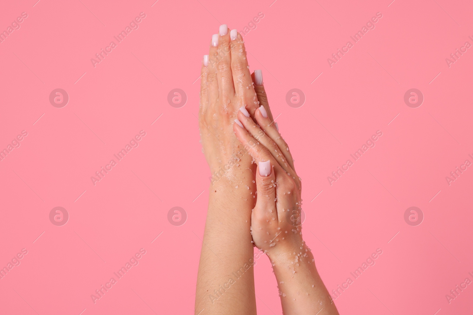 Woman applying body scrub onto her hands on pink background, closeup Photo of Woman applying body scrub onto her hands on pink background, closeup