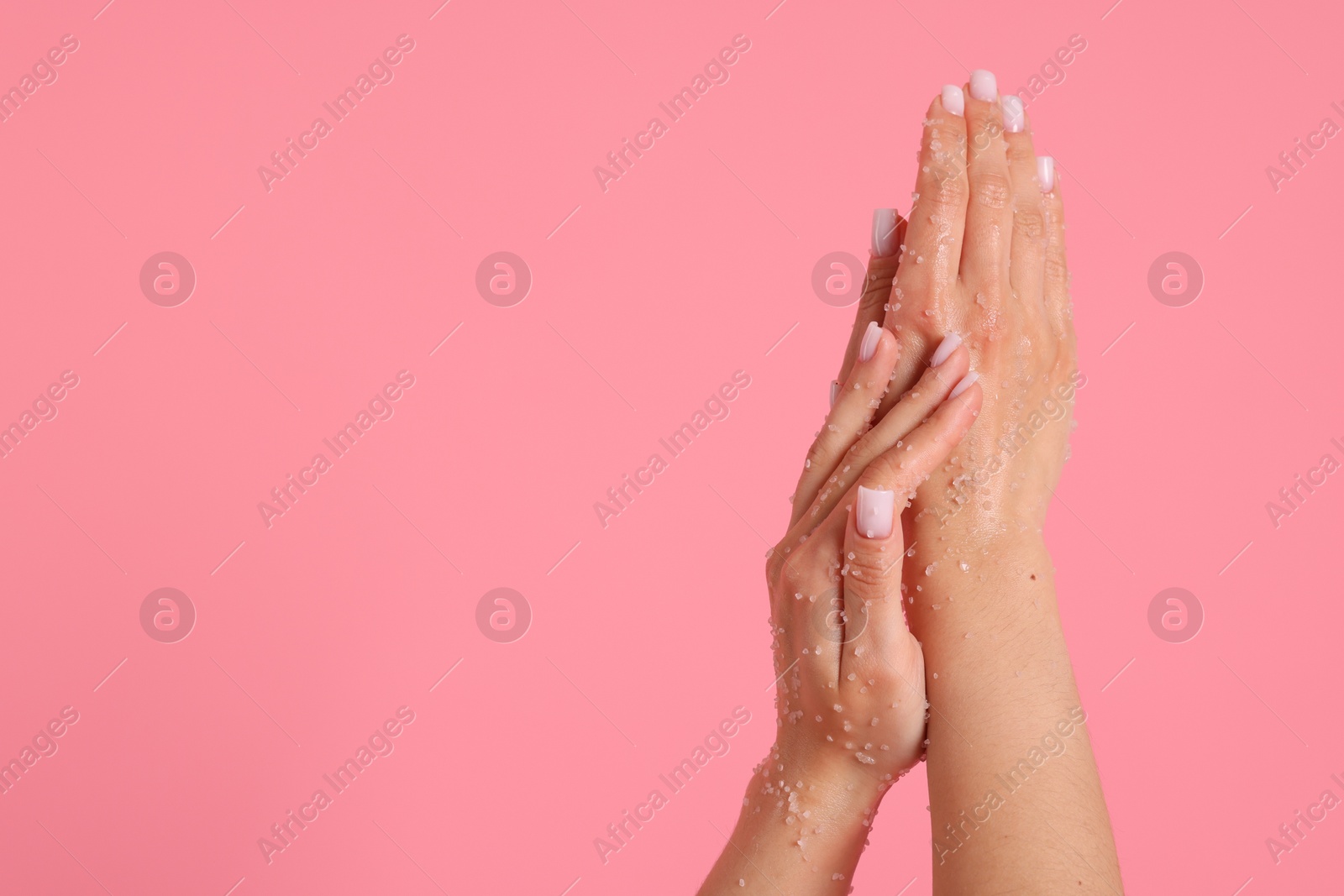 Woman applying body scrub onto her hands on pink background, closeup. Space for text Photo of Woman applying body scrub onto her hands on pink background, closeup. Space for text
