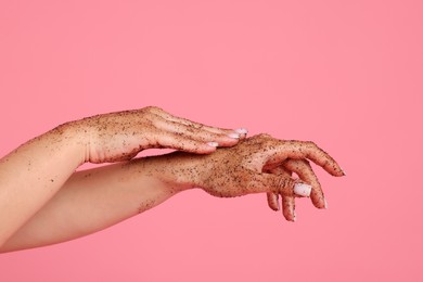 Photo of Woman applying body scrub onto her hands on pink background, closeup