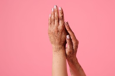 Photo of Woman applying body scrub onto her hands on pink background, closeup