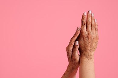 Photo of Woman applying body scrub onto her hands on pink background, closeup. Space for text
