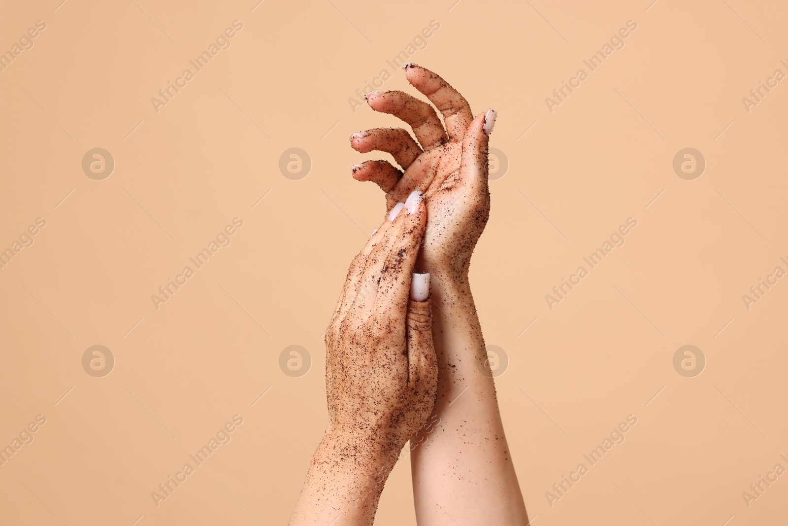 Woman applying body scrub onto her hands on beige background, closeup Photo of Woman applying body scrub onto her hands on beige background, closeup