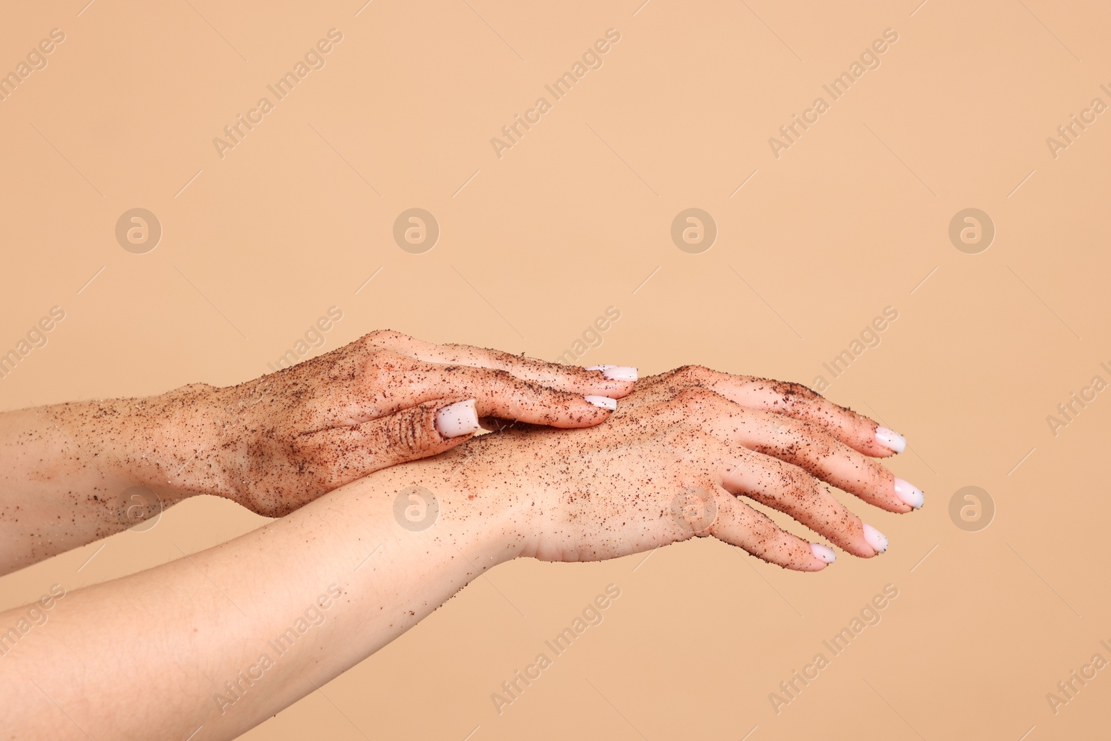 Woman applying body scrub onto her hands on beige background, closeup Photo of Woman applying body scrub onto her hands on beige background, closeup