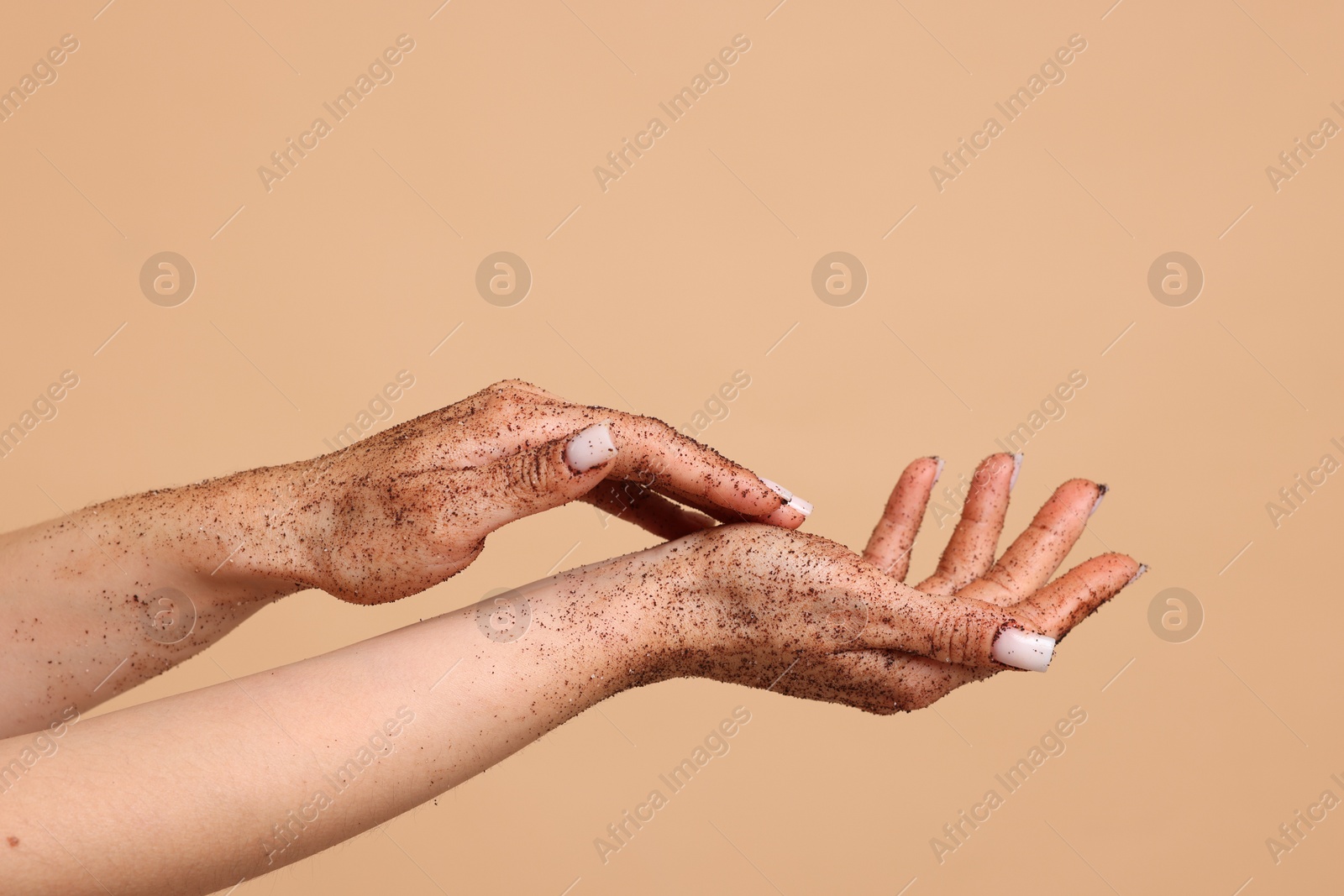 Woman applying body scrub onto her hands on beige background, closeup Photo of Woman applying body scrub onto her hands on beige background, closeup