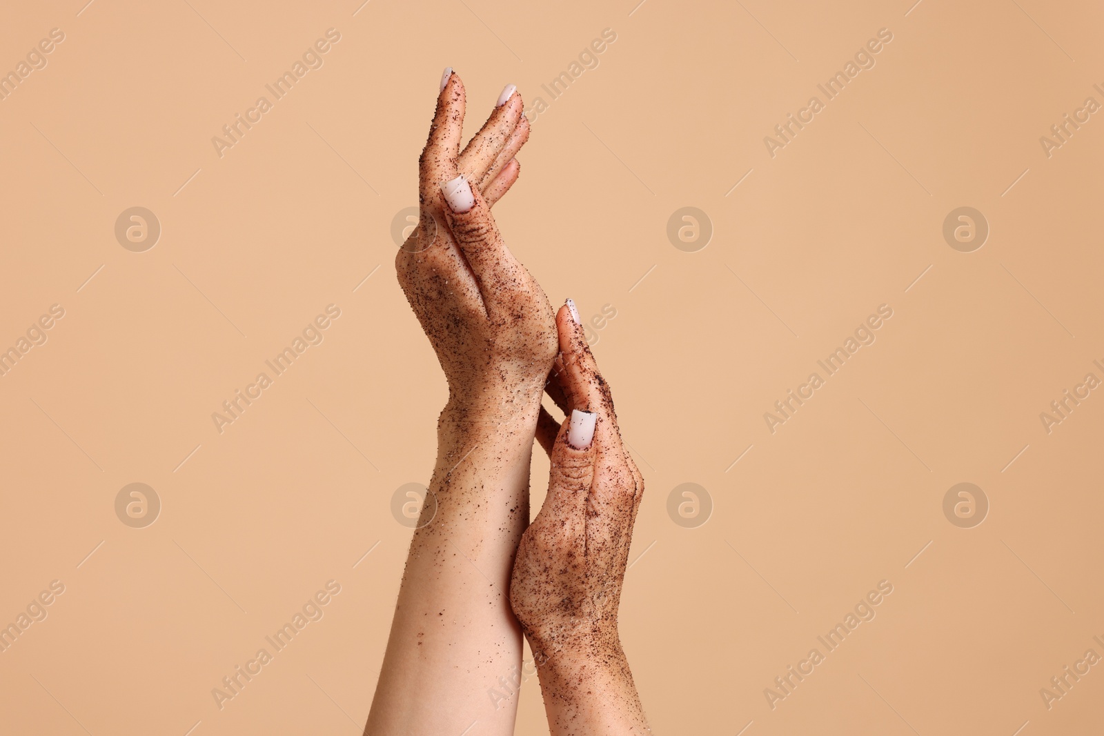 Woman applying body scrub onto her hands on beige background, closeup Photo of Woman applying body scrub onto her hands on beige background, closeup