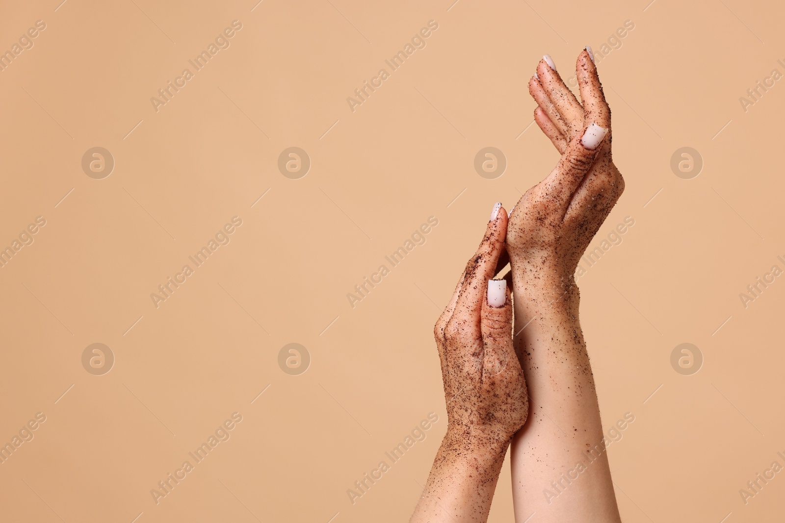 Woman applying body scrub onto her hands on beige background, closeup. Space for text Photo of Woman applying body scrub onto her hands on beige background, closeup. Space for text