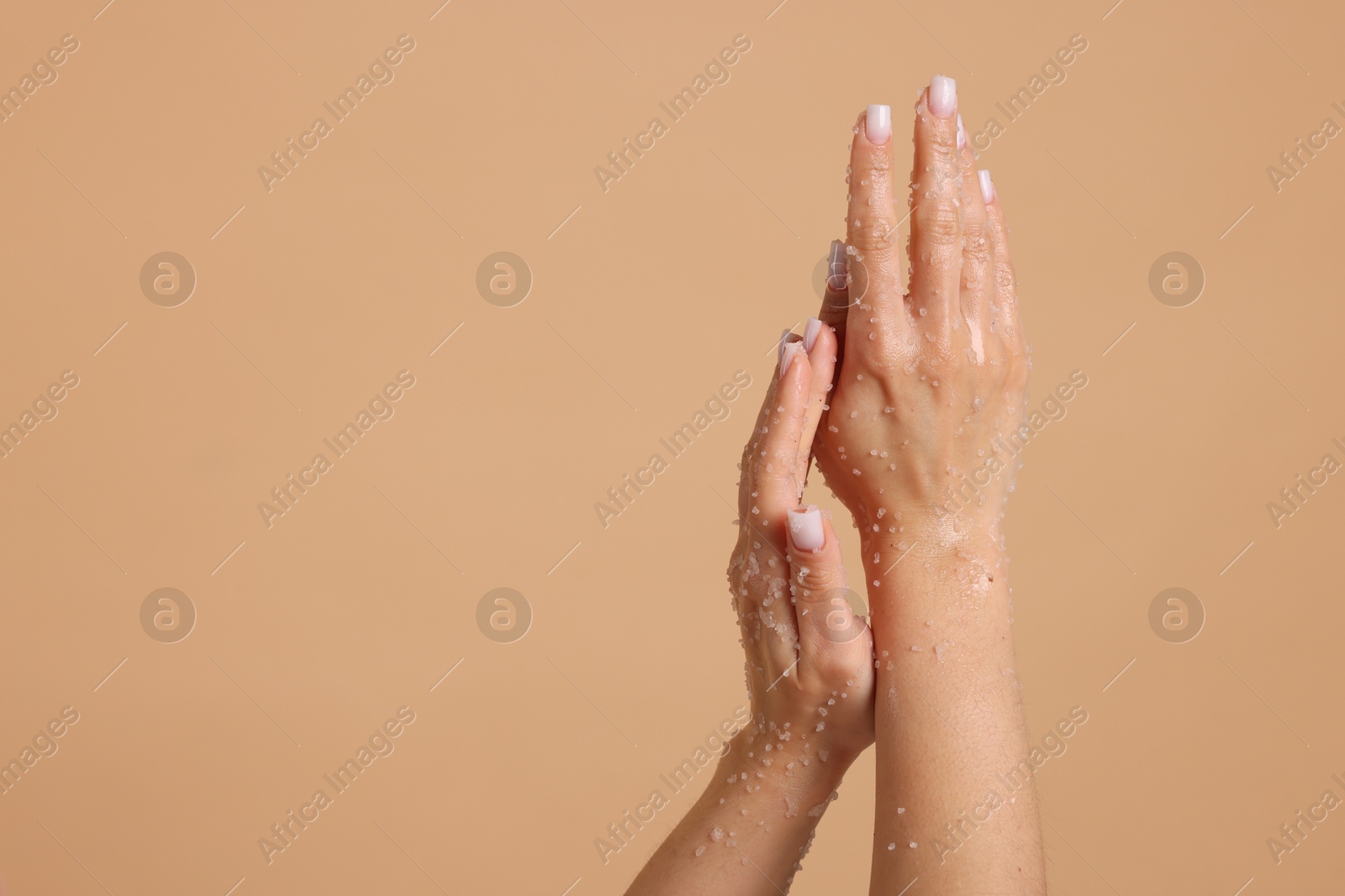 Woman applying body scrub onto her hands on beige background, closeup. Space for text Photo of Woman applying body scrub onto her hands on beige background, closeup. Space for text