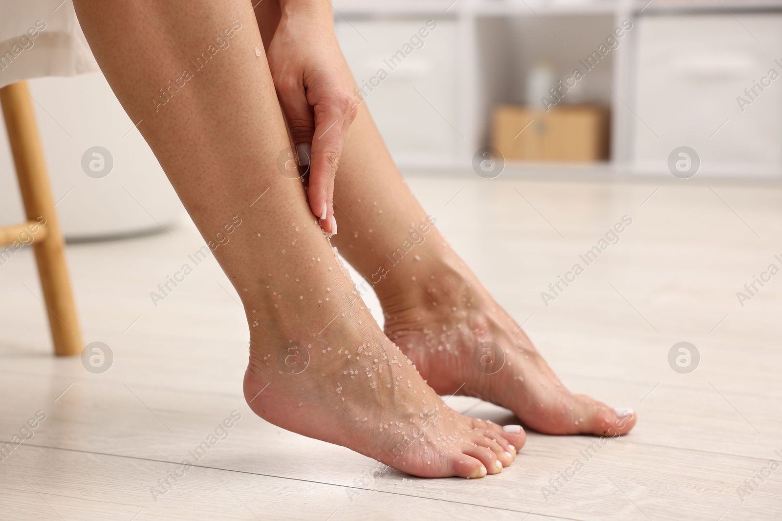 Woman applying body scrub onto her leg indoors, closeup Photo of Woman applying body scrub onto her leg indoors, closeup