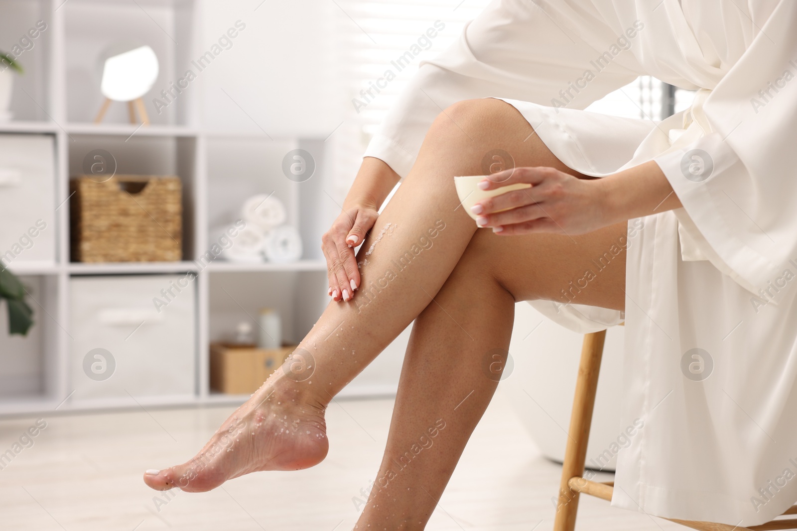 Woman applying body scrub onto her leg indoors, closeup Photo of Woman applying body scrub onto her leg indoors, closeup
