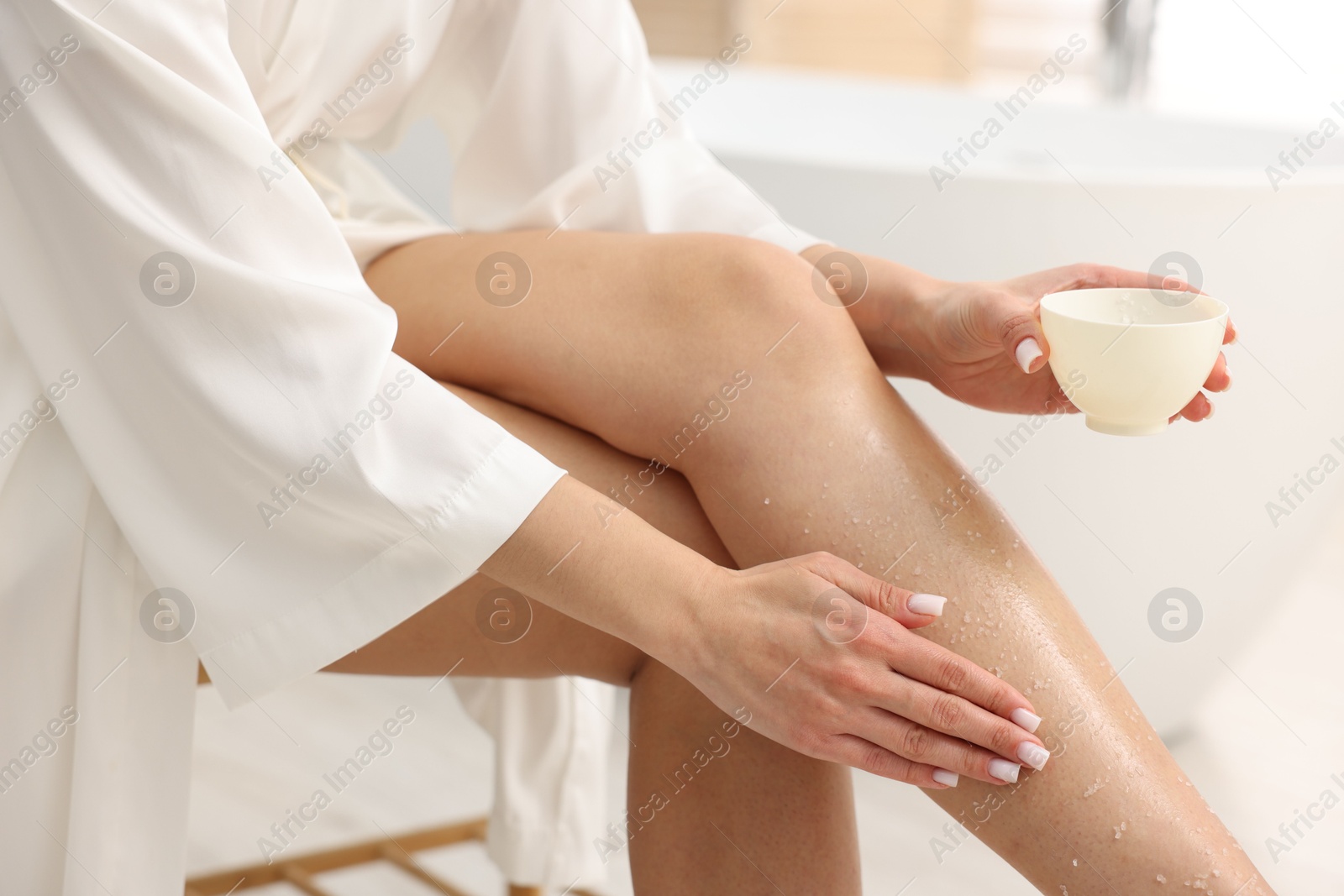 Woman applying body scrub onto her leg indoors, closeup Photo of Woman applying body scrub onto her leg indoors, closeup