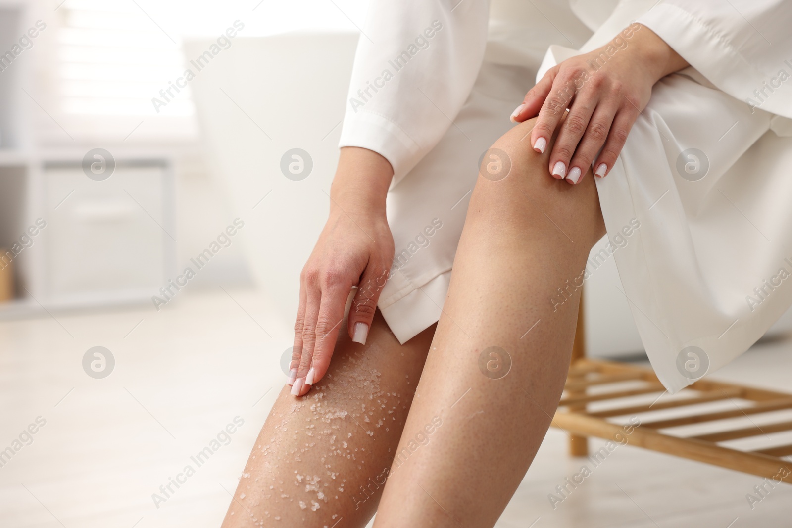 Woman applying body scrub onto her leg indoors, closeup. Space for text Photo of Woman applying body scrub onto her leg indoors, closeup. Space for text