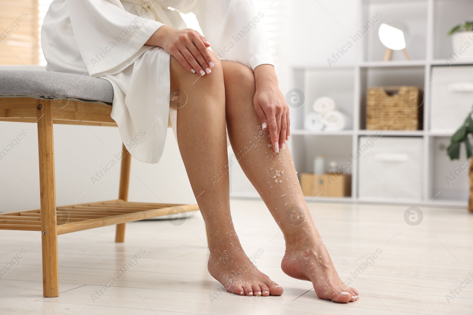 Woman applying body scrub onto her leg indoors, closeup. Space for text Photo of Woman applying body scrub onto her leg indoors, closeup. Space for text