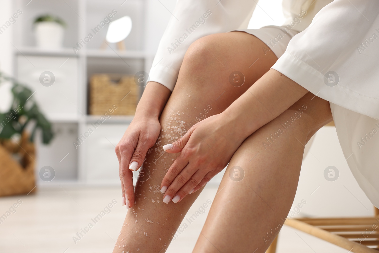 Woman applying body scrub onto her leg indoors, closeup. Space for text Photo of Woman applying body scrub onto her leg indoors, closeup. Space for text